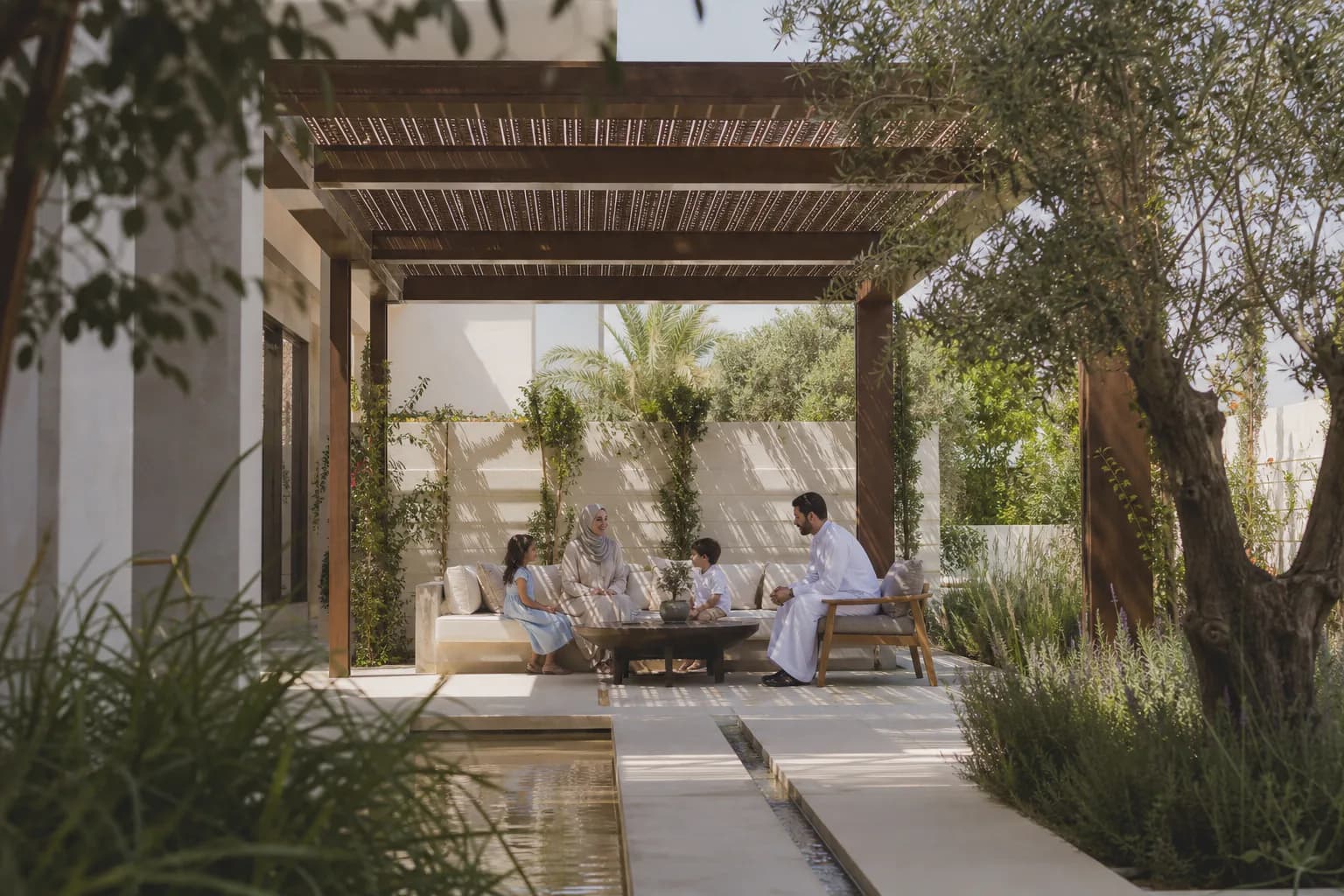 Family gathering beneath a timber pergola in a layered green garden